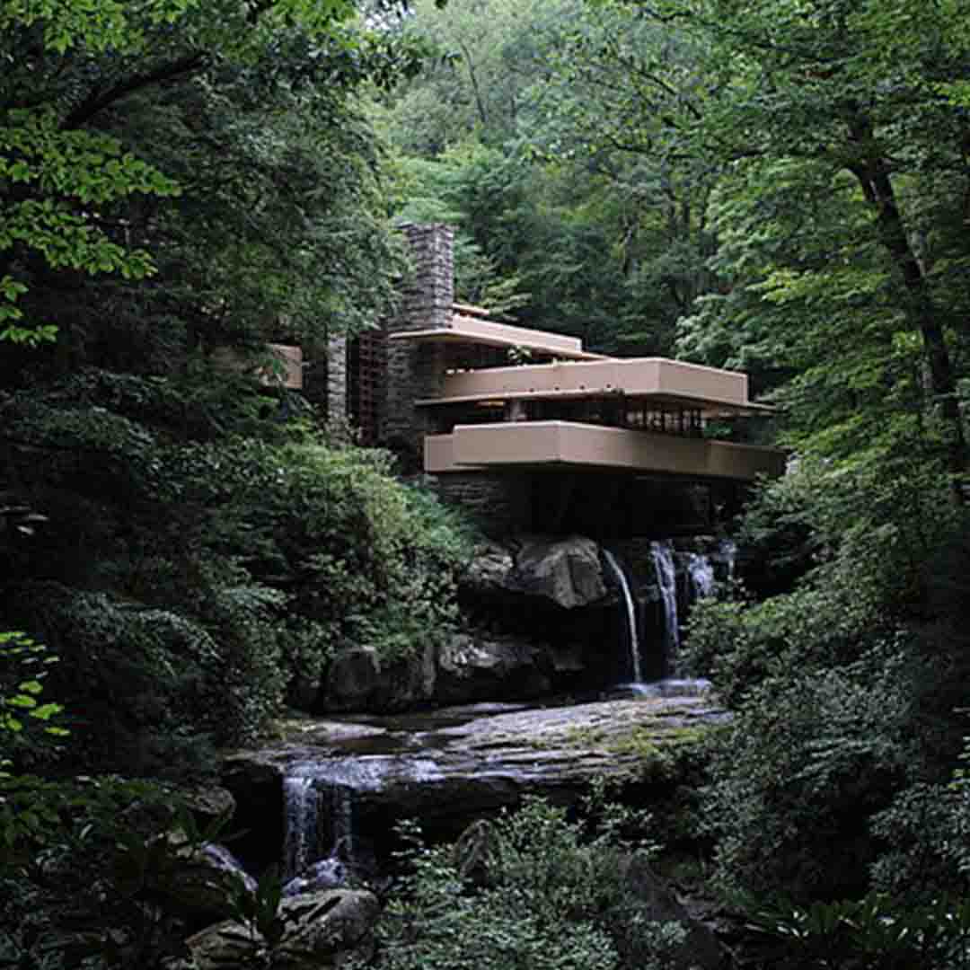 Maison avec terrasses en porte-à-faux surplombant une cascade en plein forêt.